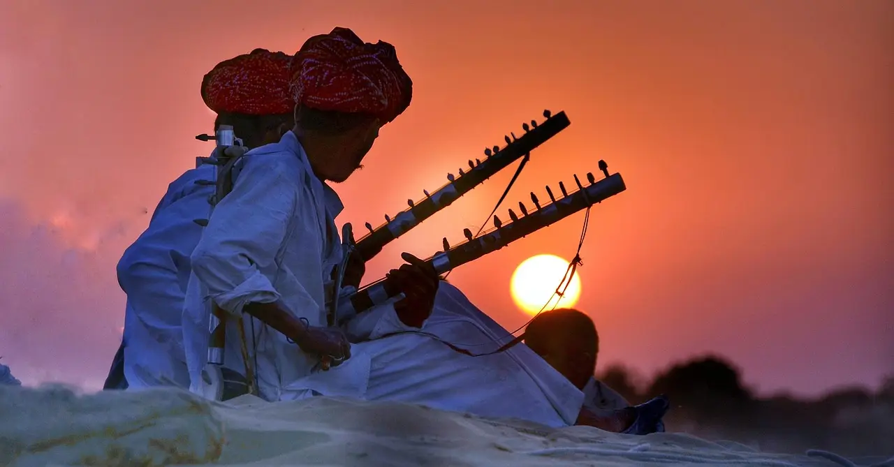Two traditional Indian musicians in a desert at sunset